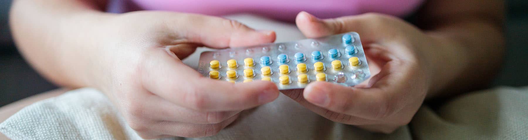 A young girl‘s hands holding a package of pills.