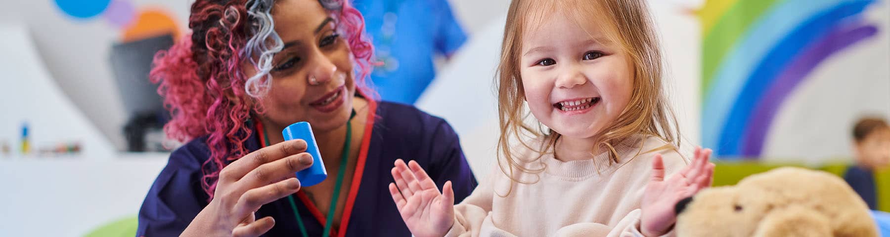 A nurse and a young girl playing and smiling.