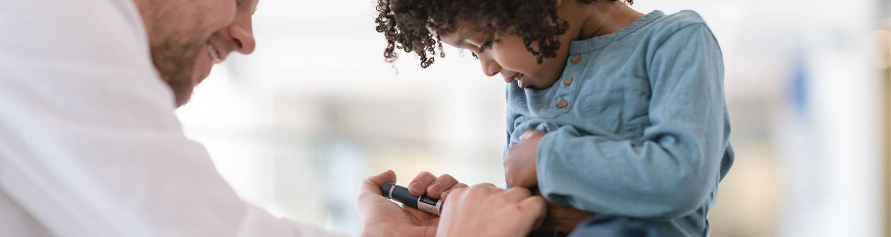 Doctor helping a young child check their blood sugar levels with a glucometer.