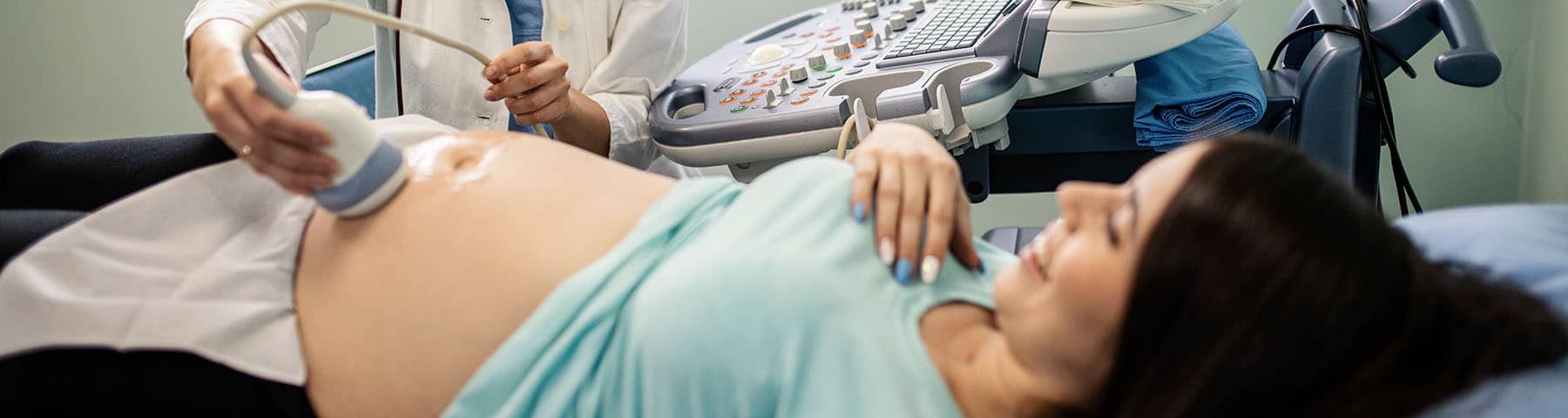 Pregnant woman receiving an ultrasound examination from a healthcare professional.