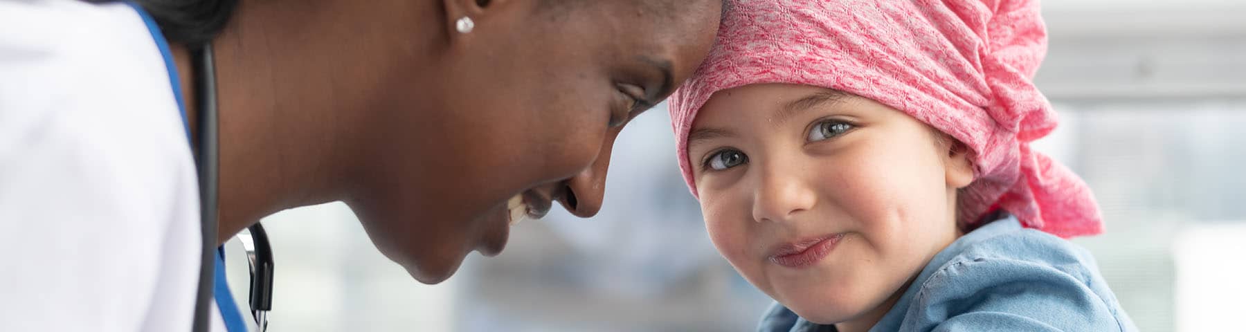 Smiling doctor sharing a close moment with a young child wearing a headscarf.