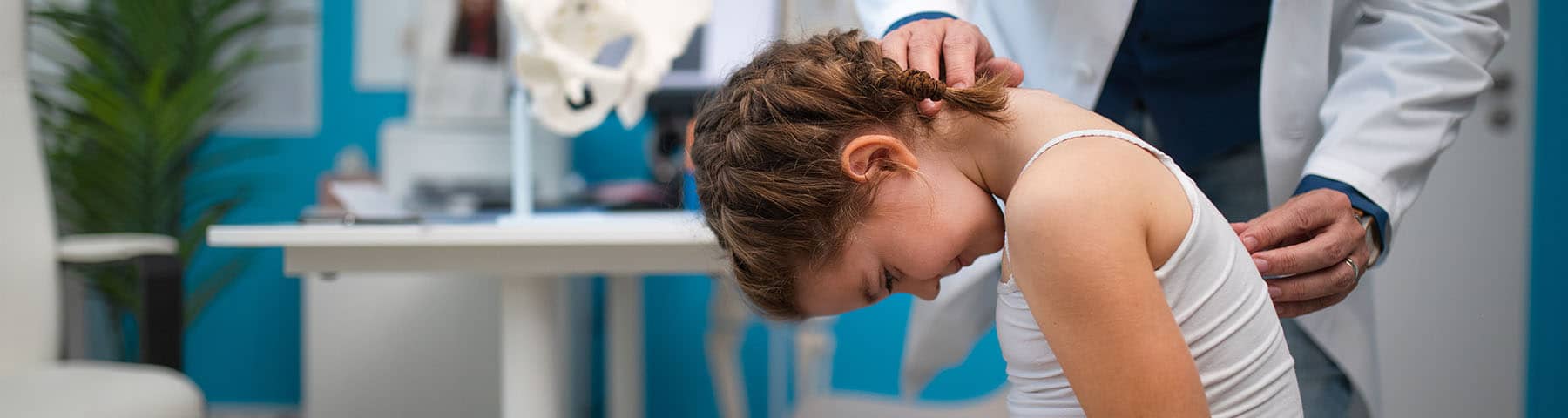 Doctor examining a young girl's spine in a pediatric orthopedic clinic.