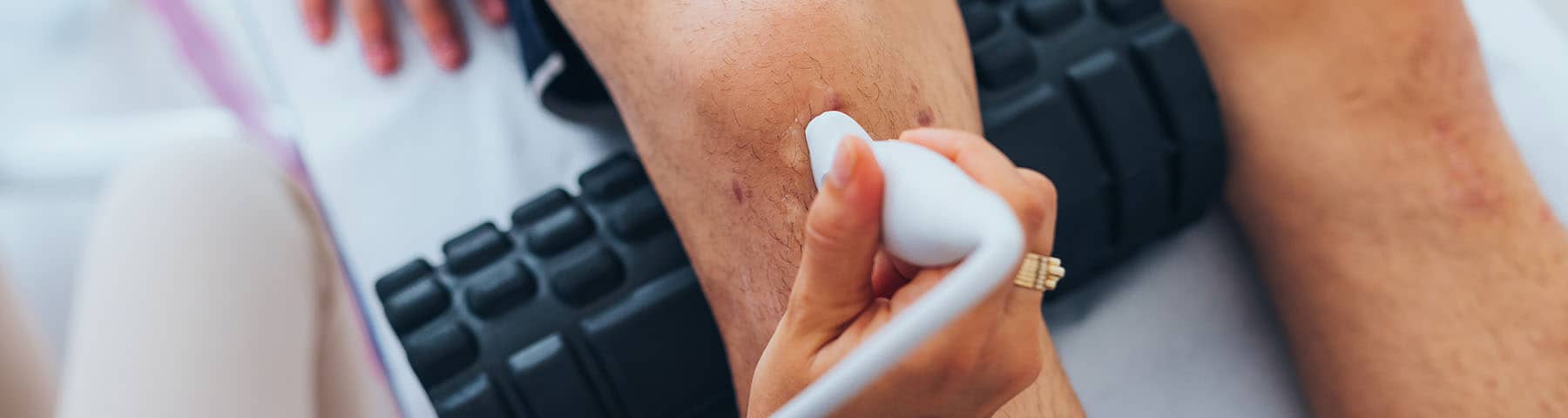 Close-up of a medical professional performing an ultrasound on a patient's leg.