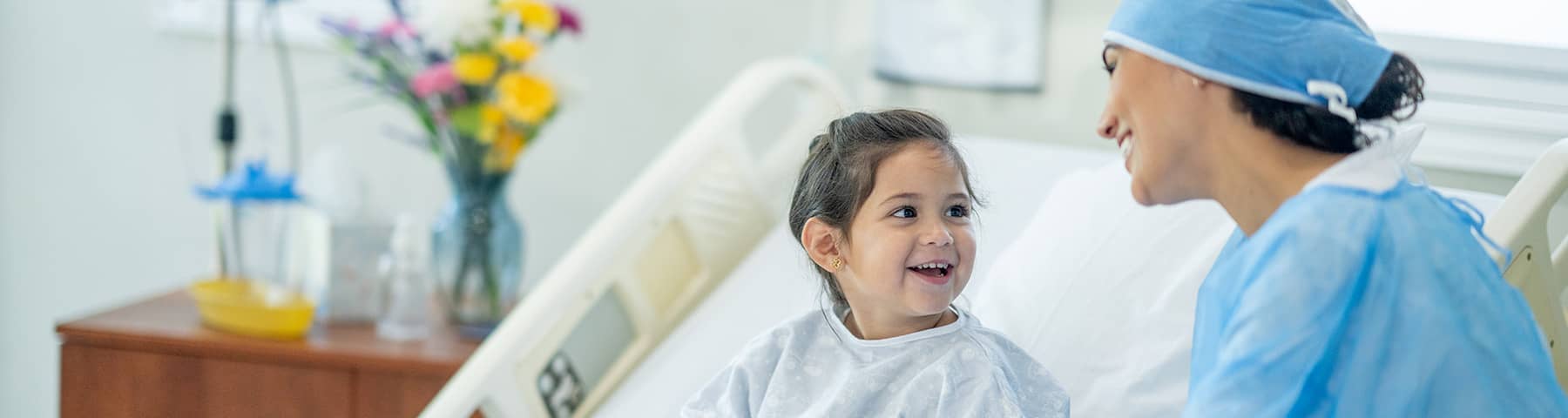 A nurse smiling at beside with a young smiling child.