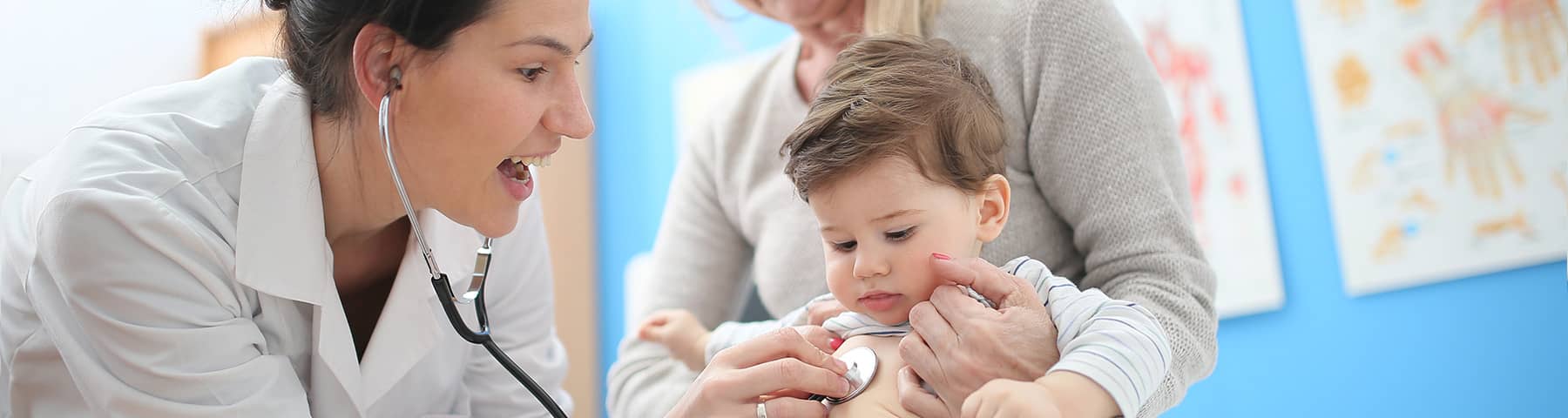 A doctor listening with a stethoscope to the heartbeat of a young boy.