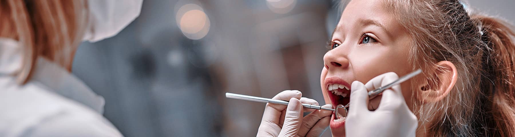 A young girl getting her teeth examined by a dentist.