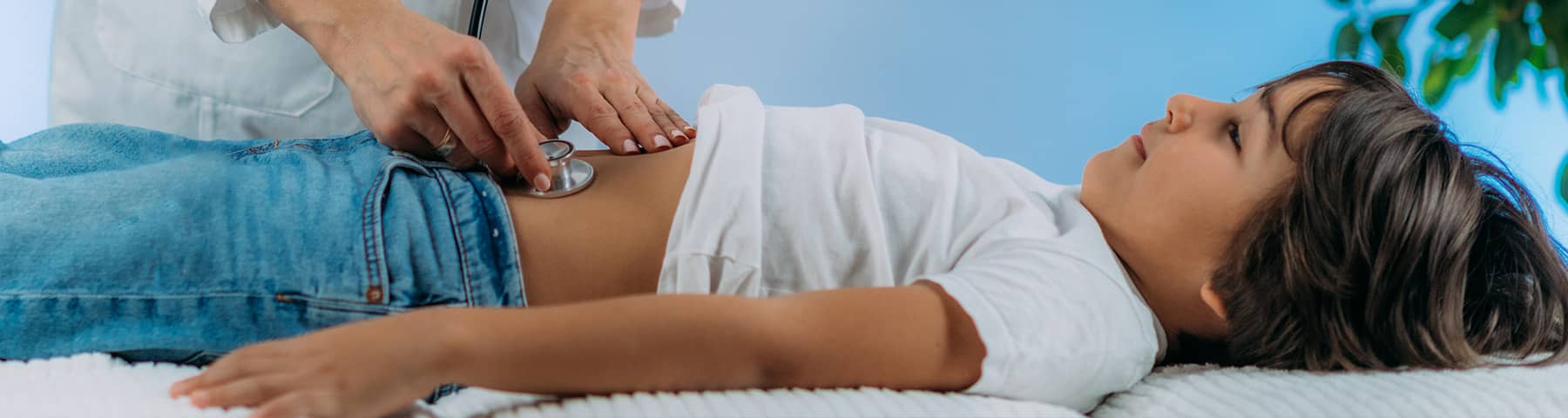 A young boy getting his abdomen examined by a doctor.