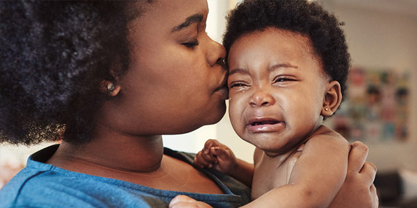 Mom kissing and consoling crying baby with concussion.