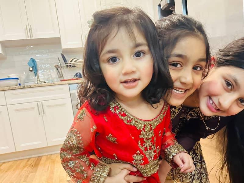 Parrizay Khan with her sisters, smiling in their family kitchen.