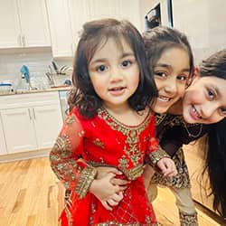 Parrizay Khan with her sisters, smiling in their kitchen together. 